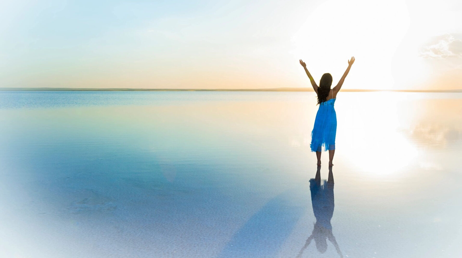 A woman standing on the beach with her arms in the air.