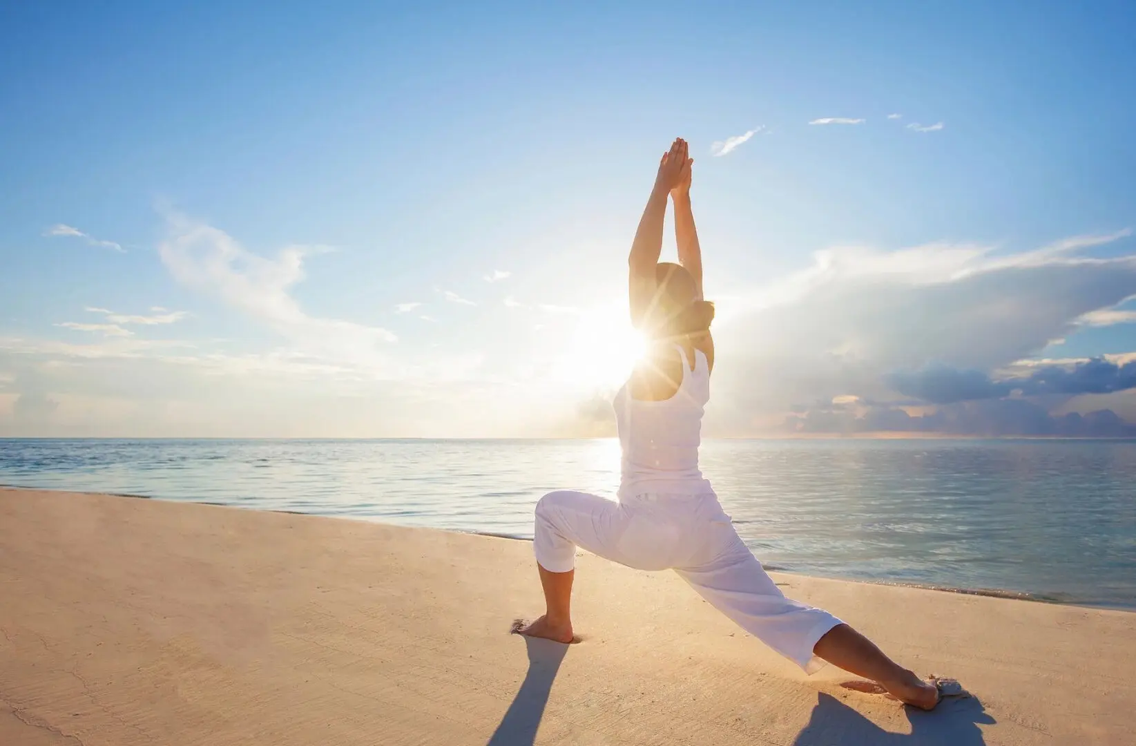 A woman is doing yoga on the beach