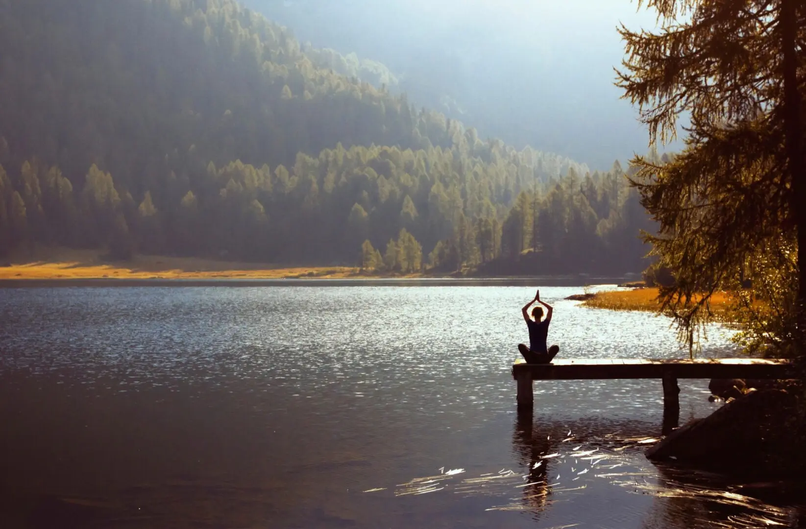 A person is sitting on the dock in front of some water