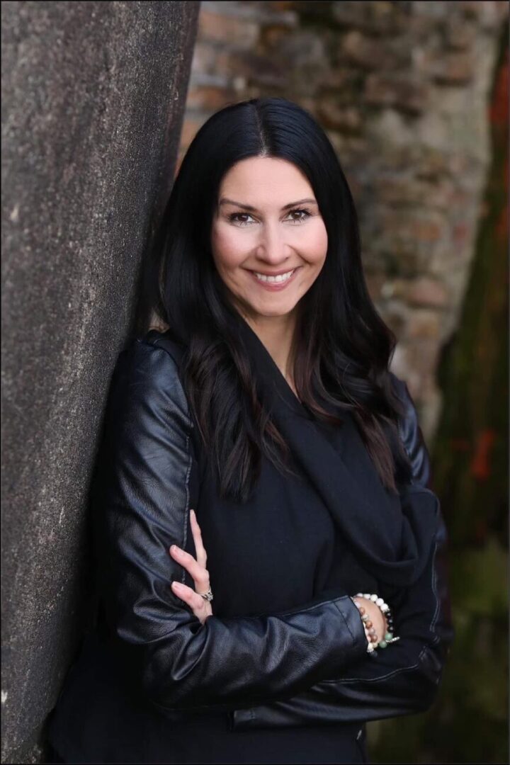 A woman leaning against a wall with her arms crossed.