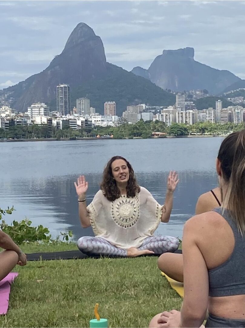 A woman sitting in the grass with her hands up.