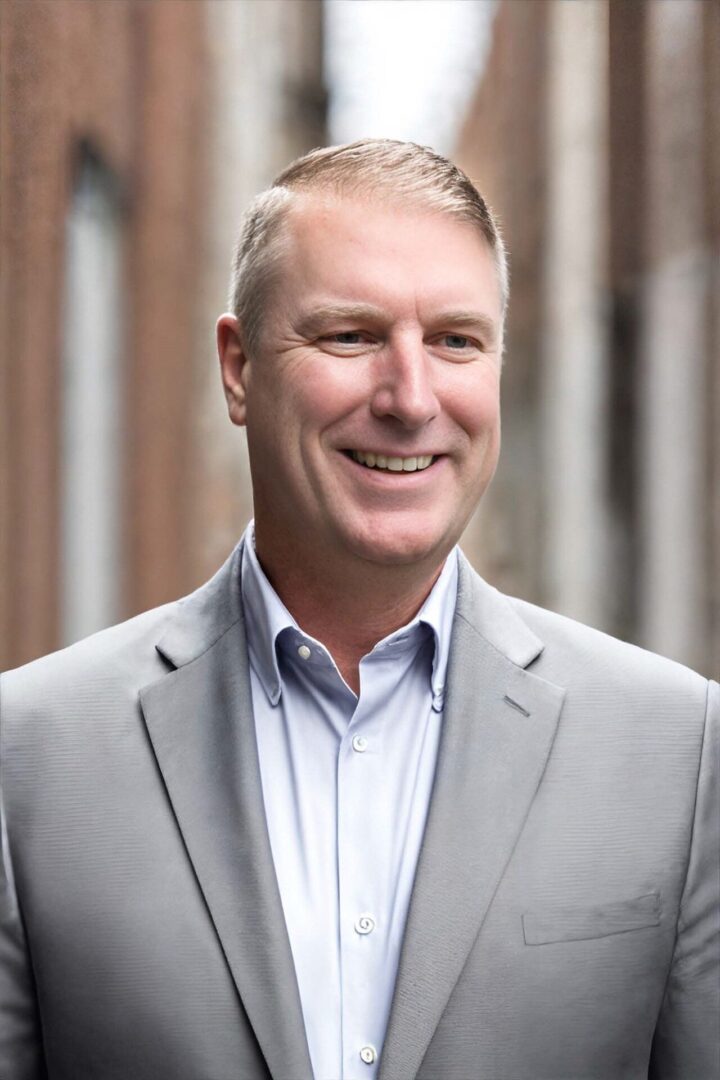 A man in a suit and tie smiling for the camera.