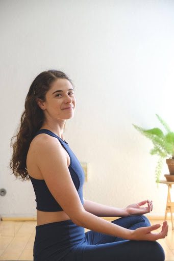 A woman is sitting in the middle of her yoga practice.