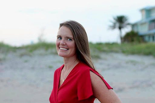 A woman in red shirt standing on beach.