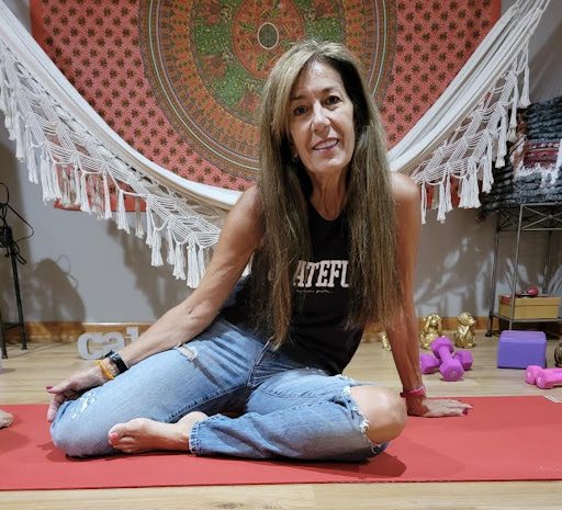 A woman sitting on the ground in a yoga pose.