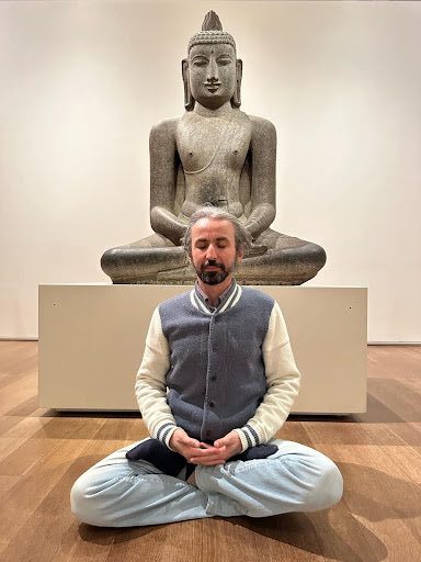 A man sitting in front of an empty buddha statue.