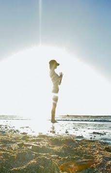 A person standing on the beach in front of a sun.