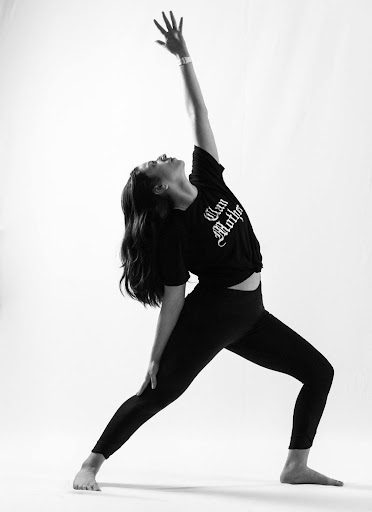 A woman in black shirt and leggings playing with a ball.