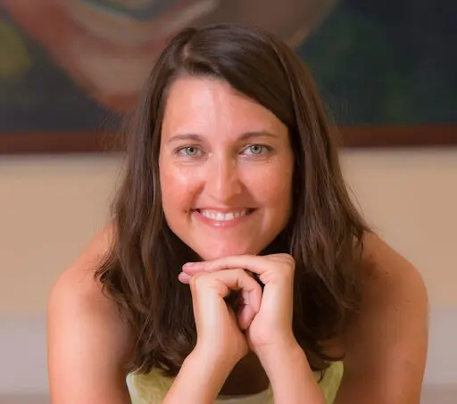 A woman smiling with her hands on the chin.