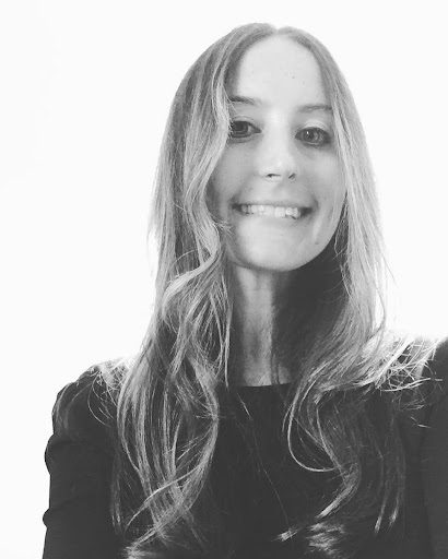 A woman smiling for the camera in front of a white background.