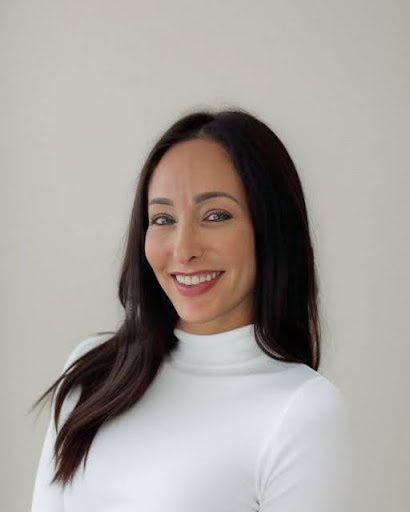 A woman in white shirt smiling for the camera.