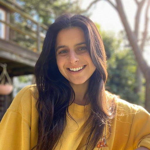 Smiling woman with long dark hair in a yellow sweater.