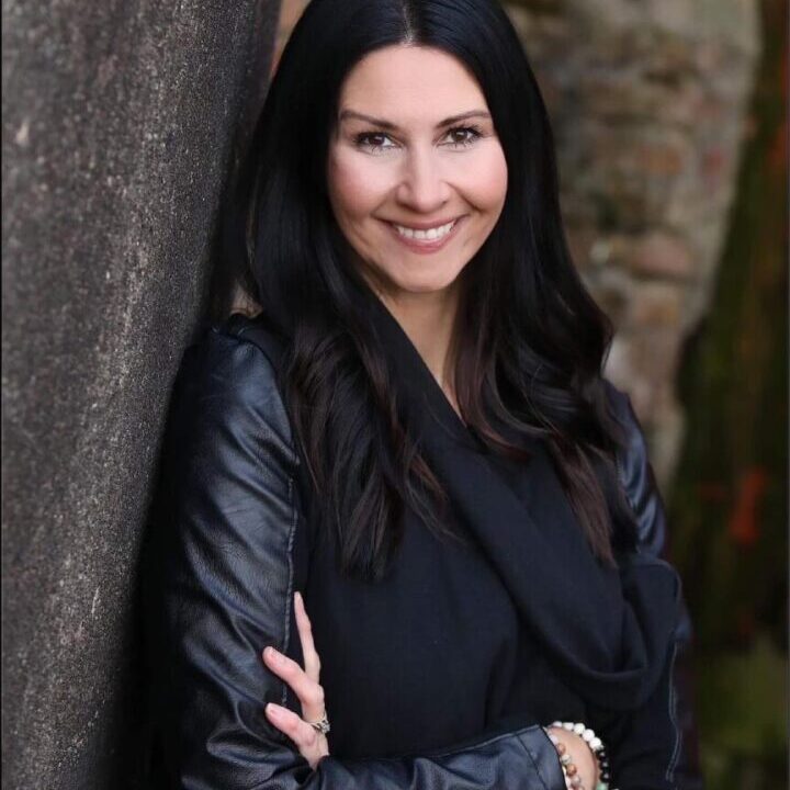 A woman leaning against a wall with her arms crossed.