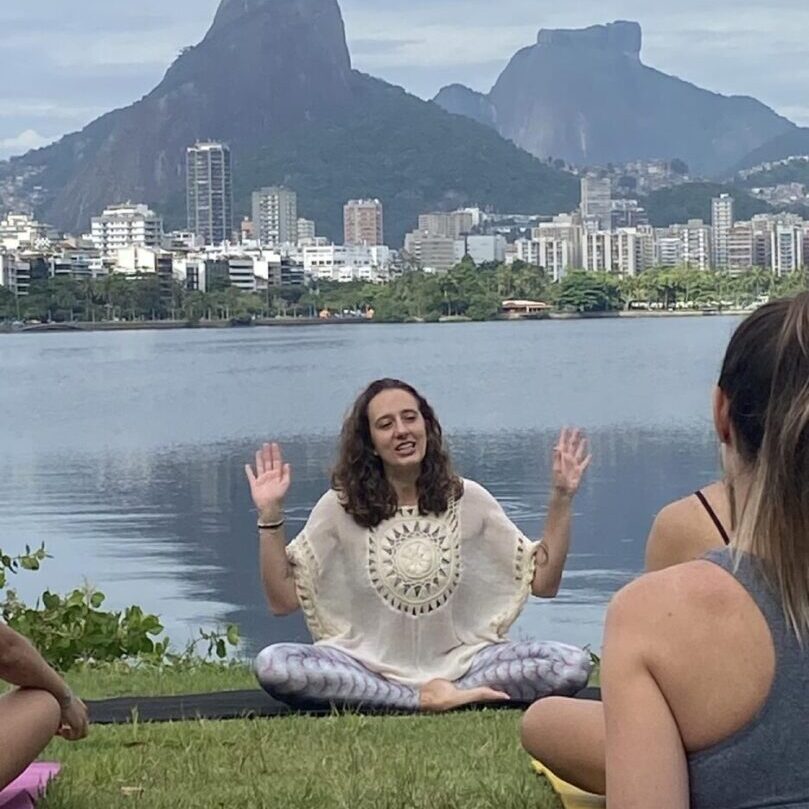 A woman sitting in the grass with her hands up.