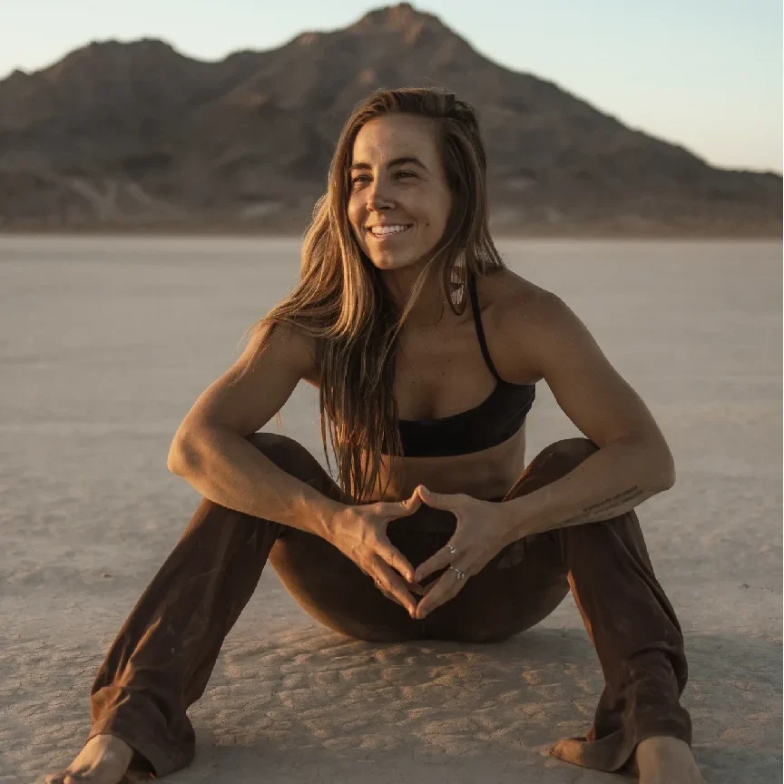 Smiling woman in brown pants, desert landscape.