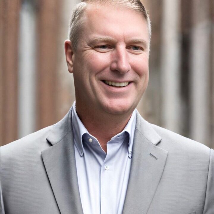 A man in a suit and tie smiling for the camera.