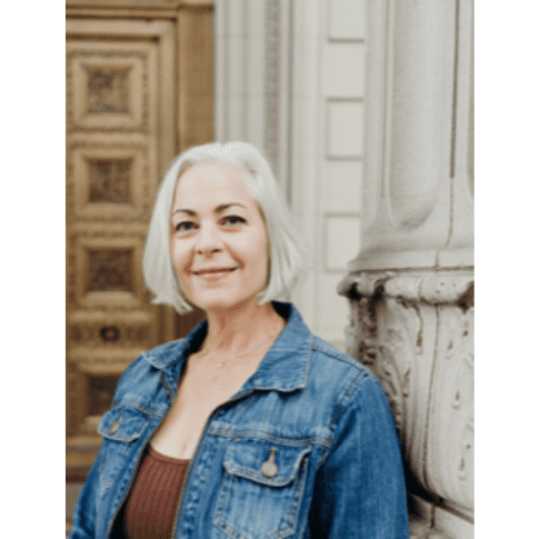 A woman with white hair wearing a jean jacket.