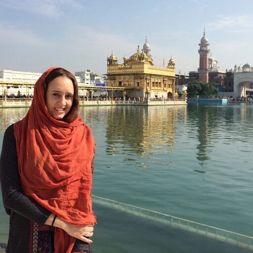 A woman in red scarf standing next to water.