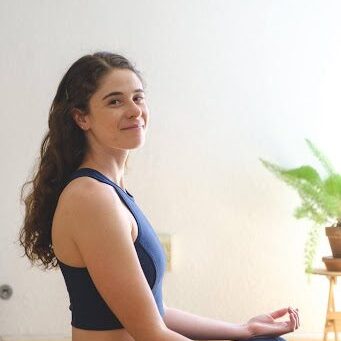 A woman is sitting in the middle of her yoga practice.