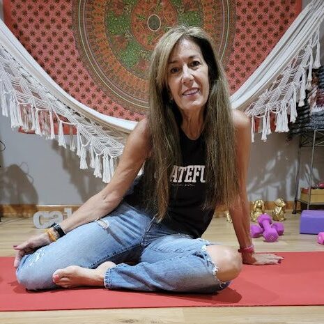 A woman sitting on the ground in a yoga pose.