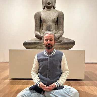 A man sitting in front of an empty buddha statue.