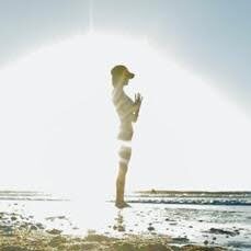 A person standing on the beach in front of a sun.