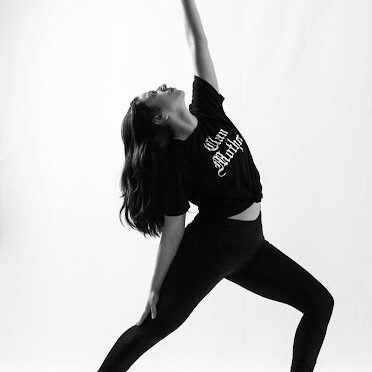 A woman in black shirt and leggings playing with a ball.