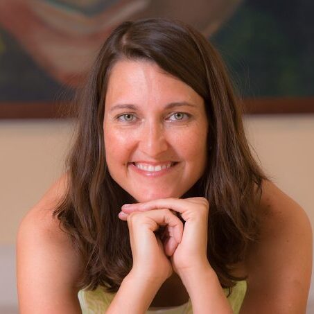 A woman smiling with her hands on the chin.